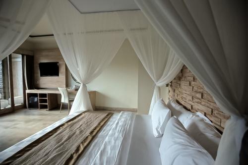 a bedroom with a large white bed with curtains at Angsoka Bungalow in Ubud
