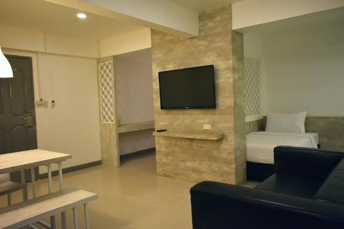 a hotel room with a bed and a flat screen tv at Loyy Hotel in Chiang Mai