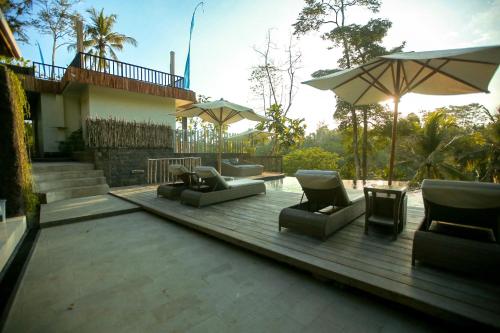 a patio with couches and umbrellas on a deck at Angsoka Bungalow in Ubud