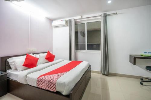 a bedroom with a bed with red pillows and a window at MALAPPURAM RESIDENCY in Malappuram
