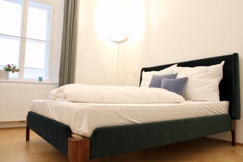 維也納的住宿－Oskar Kokoschka - City Apartment Downtown Vienna，一张带黑色框架和白色床单及枕头的床