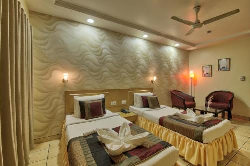 a hotel room with two beds and a chair at Vishwaratna Hotel in Guwahati