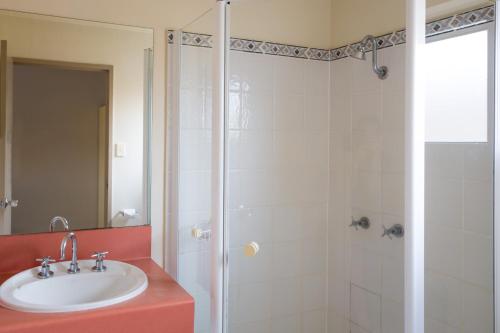 
a bathroom with a shower, sink, and mirror at Cairns Colonial Club Resort in Cairns
