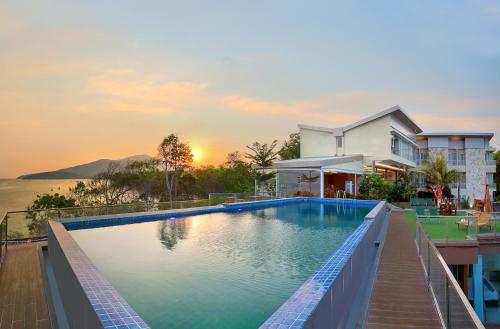 a villa with a swimming pool in front of a house at Royal Ocean View Beach Resort in Karimunjawa