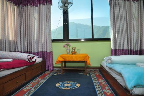 una stanza con due letti, un tavolo e una finestra di Nagarjun Home Stay a Kathmandu