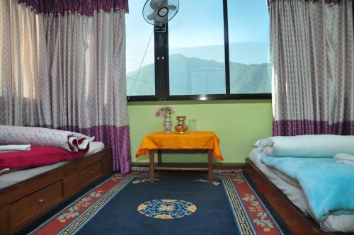 a room with two beds and a table and a window at Nagarjun Home Stay in Kathmandu