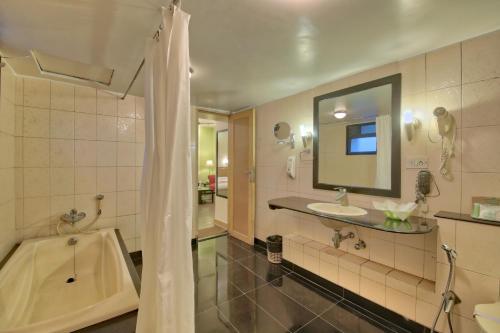 a bathroom with a tub and a sink and a mirror at Vishwaratna Hotel in Guwahati