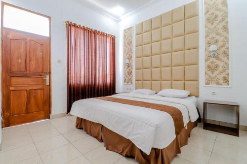 a bedroom with a large bed with a wooden door at Griya Limasan Gunung Kidul in Wonosari