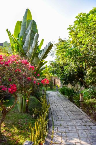 a stone path in a garden with flowers and plants at Owa Lodge Areguling in Kuta Lombok
