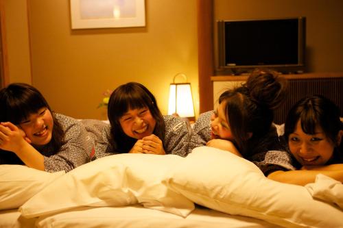a group of three women laying on a bed at Miyajima Grand Hotel Arimoto in Miyajima