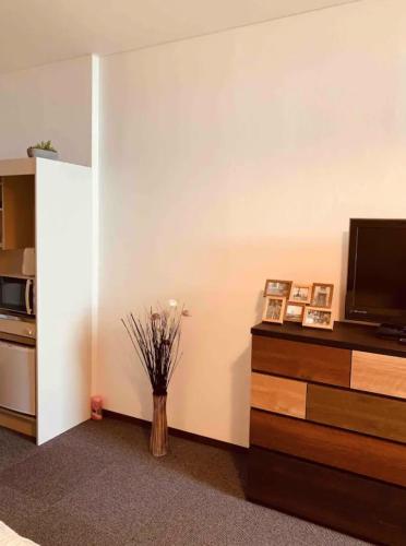 a living room with a tv and a vase with flowers at ひまわり 向日葵 himawari in Takamatsu