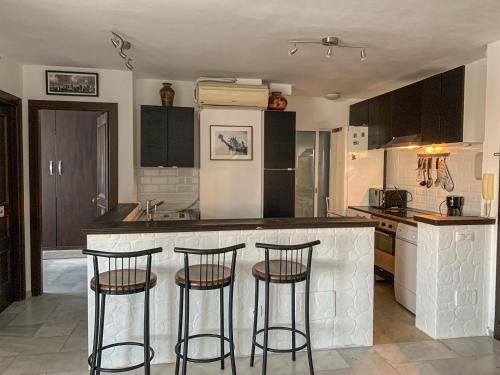 uma cozinha com um balcão e três bancos de bar em Apartament Benalmadena Marina SOL em Benalmádena