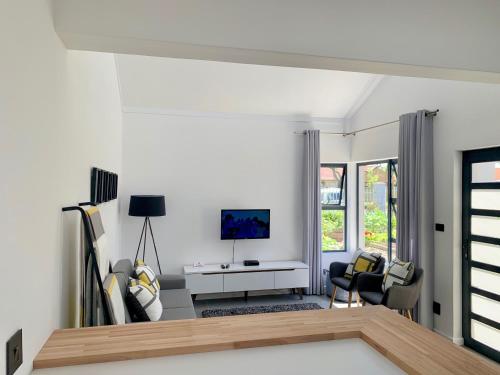a living room with white walls and a tv at Lorelei Guest House in George