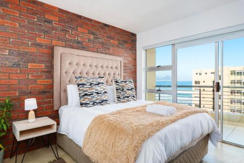 una camera da letto con un muro di mattoni e un grande letto di Modern 1 Bedroom in Blouberg a Città del Capo