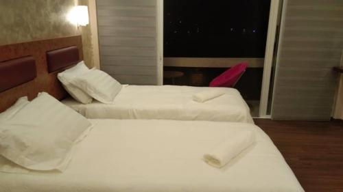 two beds in a hotel room with a window at Leely Garden Valley Lodge Tambunan in Tambunan