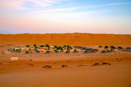 a desert area with a few palm trees at Arabian Oryx Camp in Shāhiq