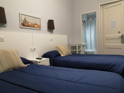 2 camas azules en una habitación con ventana en Hostal Lesseps, en Barcelona