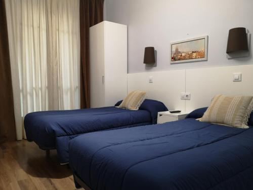 two beds in a hotel room with blue sheets at Hostal Lesseps in Barcelona