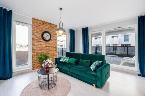 un soggiorno con divano verde e orologio di Apartments Poznań Niedziałkowskiego by Renters a Poznań