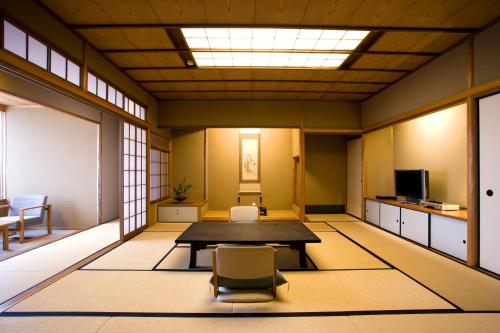 a room with a table and a chair in it at Miyajima Grand Hotel Arimoto in Miyajima