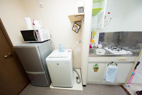 a small kitchen with a refrigerator and a sink at Cozy house 307 free wifi a rented electric bicycle in Kyoto