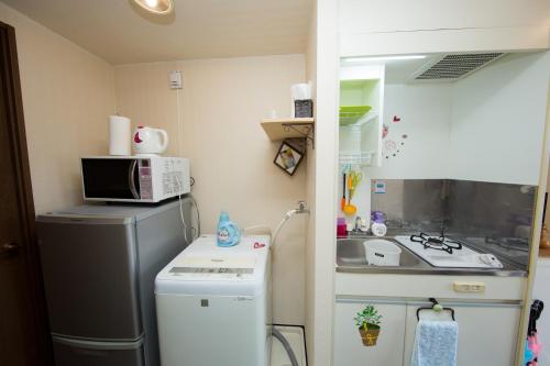 a small kitchen with a microwave and a refrigerator at Cozy house 307 free wifi a rented electric bicycle in Kyoto