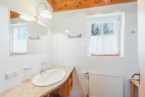 ein weißes Badezimmer mit Waschbecken und Fenster in der Unterkunft Alpine Cabin in Klippitztorl