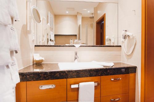 a bathroom with a sink and a large mirror at Ringhotel Teutoburger Wald in Tecklenburg