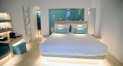 a bedroom with a large white bed with blue pillows at Mykonos Moussa in Agios Ioannis Mykonos