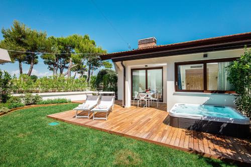 a deck with a hot tub and two chairs on it at Hotel San Giorgio Resort 4S in Caorle
