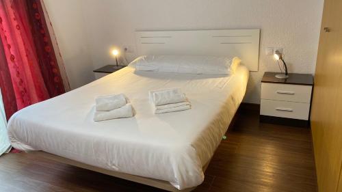 ein Schlafzimmer mit einem weißen Bett mit zwei Handtüchern darauf in der Unterkunft P&C Dolsa in Pas de la Casa