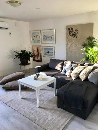 a living room with a black couch and a white coffee table at Rymlig lägenhet i avdelat hus med egen parkering in Käglinge