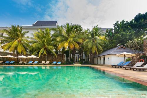 a swimming pool with chairs and palm trees at Lotus Blanc Hotel in Siem Reap