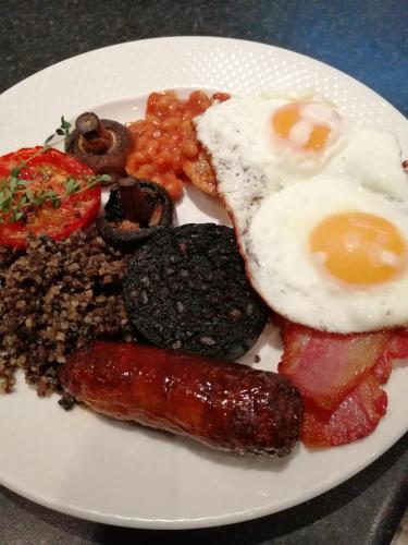 een bord ontbijtproducten met eieren, worst en bonen bij Allerdale Guest House in Keswick