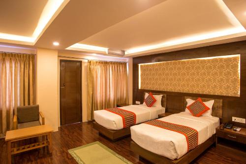 a hotel room with two beds and a chair at Hotel Yellow Pagoda Pokhara in Pokhara