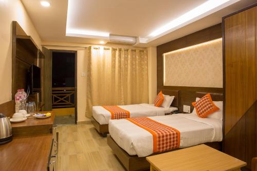 a hotel room with two beds and a television at Hotel Yellow Pagoda Pokhara in Pokhara