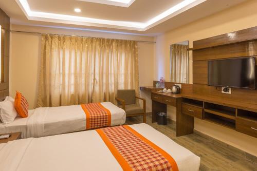 a hotel room with two beds and a flat screen tv at Hotel Yellow Pagoda Pokhara in Pokhara