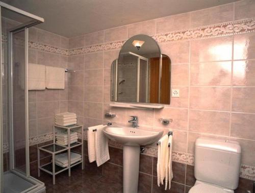 a bathroom with a sink and a toilet and a mirror at Castel Appartemente in Saas-Grund