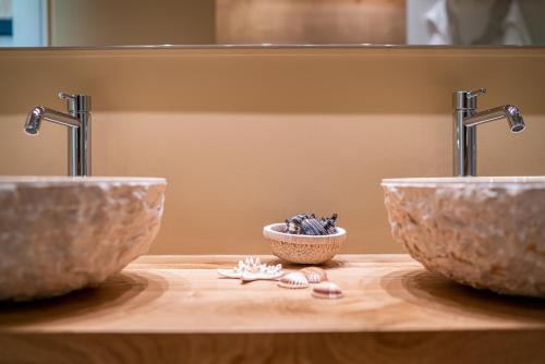two sinks on top of a wooden counter with shells at Hotel San Giorgio Resort 4S in Caorle