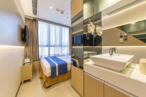een badkamer met een wastafel en een bed in een kamer bij Lumine Hotel in Hong Kong