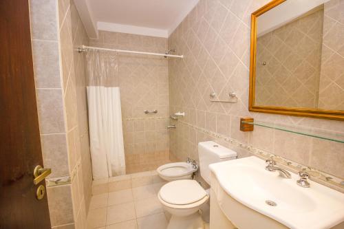 een badkamer met een toilet, een wastafel en een spiegel bij La Casona de Valeria in Valeria del Mar