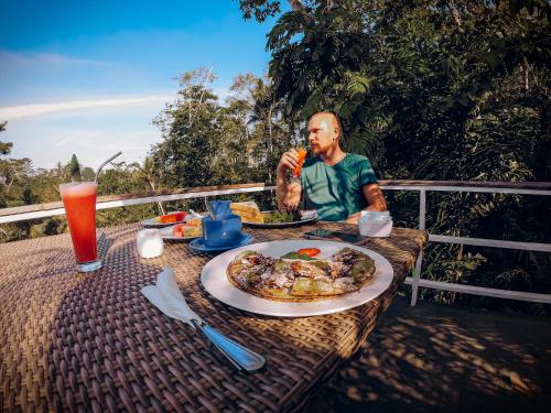 Ein Mann, der an einem Tisch mit einem Teller Essen sitzt. in der Unterkunft Angsoka Bungalow in Ubud