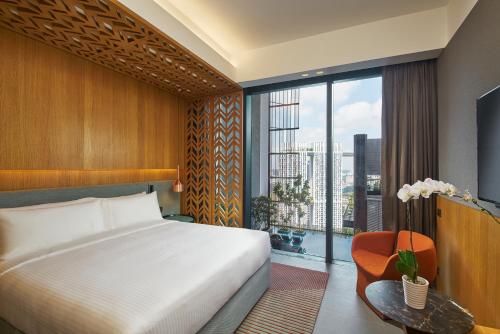 sypialnia z łóżkiem i dużym oknem w obiekcie Oasia Hotel Downtown, Singapore by Far East Hospitality w Singapurze