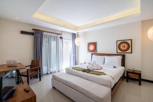 a bedroom with a bed and a desk with a laptop at Layantara Villas in Layan Beach
