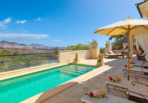 a swimming pool with an umbrella and chairs at Royal Garden Villas, Luxury Hotel in Adeje