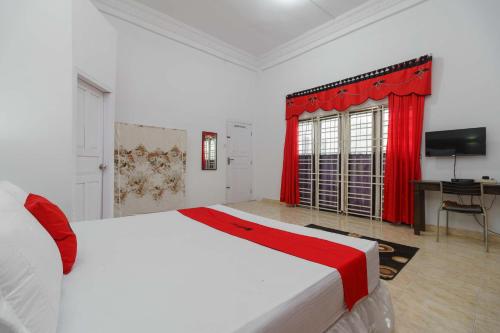 a bedroom with a white bed and a red curtain at RedDoorz Syariah near Museum Tsunami Aceh 2 in Geutieue