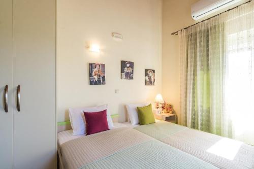 a bedroom with a bed with colorful pillows and a window at Villa Chara Chania in Agia Marina Nea Kydonias