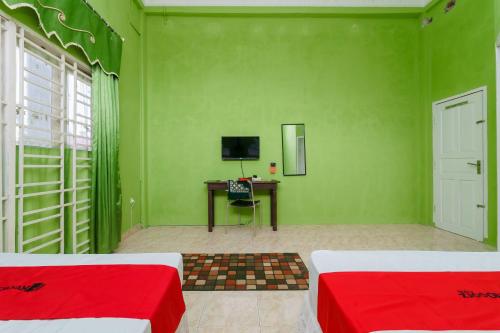 a green room with two beds and a desk with a computer at RedDoorz Syariah near Museum Tsunami Aceh 2 in Geutieue