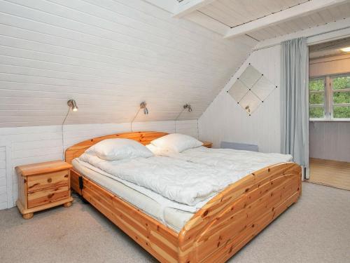 ein Schlafzimmer mit einem Holzbett in einem Zimmer in der Unterkunft Holiday Home Grævlingevej II in Mosevrå