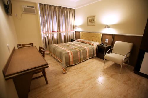 um quarto com uma cama, uma secretária e uma cadeira em Soneca Plaza Hotel em São Paulo